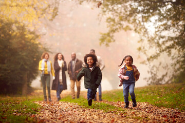 Smiling Multi-Generation Family Having Fun With Children Walking Through Autumn Countryside Together