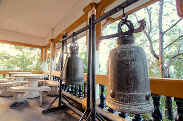 Fototapeta na wymiar Ancient bells hanging on the terrace with marble benches and tables.