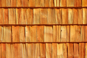 the texture of the wooden shingles covering the wall of the house