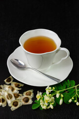 Moringa Tea in white cup with fresh green leaf and flower on wooden background. Moringa oleifera tropical herb healthy lifestyle concept.