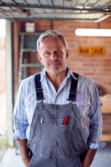 Portrait Of Mature Male Wearing Overalls In Garage Workshop