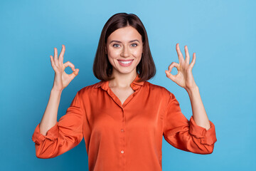 Portrait of attractive cheerful content girl showing double ok-sign ad isolated over bright blue...