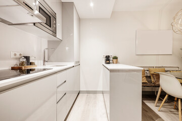Fototapeta na wymiar kitchen with gray lacquered furniture, stainless steel appliances and island with white stone countertop