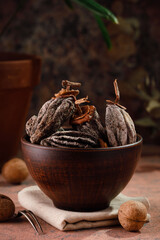 dried persimmons in a clay cup and walnuts on a dark brown background. Dried fruits