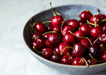 Plate of fresh raw cherries. Close up of bright red cherry with drops of water. Healthy eating concept. Vitamin rich diet.
