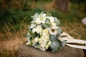 A beautiful bouquet of the bride lies on a stump on a summer lawn