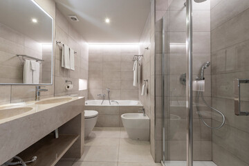 bathroom with marble sink and matching marble floors and walls with shower and frameless wall mirror, towel racks with clean towels and chrome fixtures, shower and LED lights