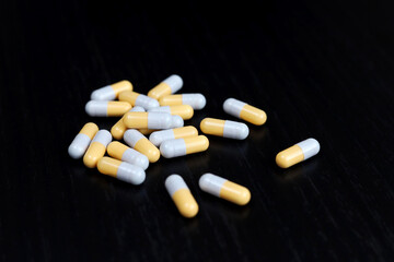 Pills on a black wooden table, medication in capsules. Pharmacy, antibiotics or vitamins