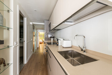Open kitchen as a passageway in a vacation rental home with gray lacquered furniture and decorative...