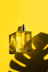 Transparent bottle of perfume with label on a yellow background. Fragrance presentation with...