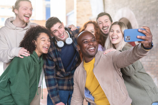 Multiracial young people group taking selfie with a smartphone - Happy lifestyle concept with young students having fun together - focus on black man.