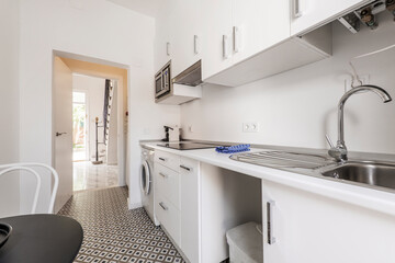 White furniture kitchen with matching white countertop and hydraulic tile floors in a single-family house