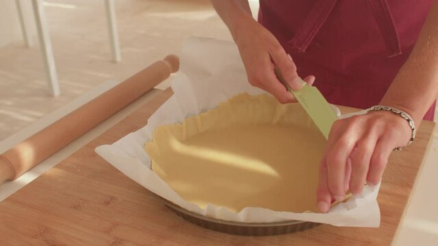 Cutting dough on a baking sheet before baking. Make a straight edge. Raw preparation to bake a feather. Turner's hands.