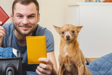 Happy young man with his cute small dog, man holds passports in his hands.