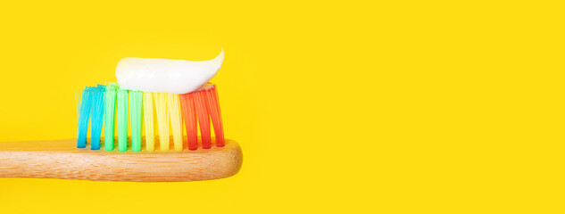 bamboo toothbrush with toothpaste over yellow background, panoramic layout