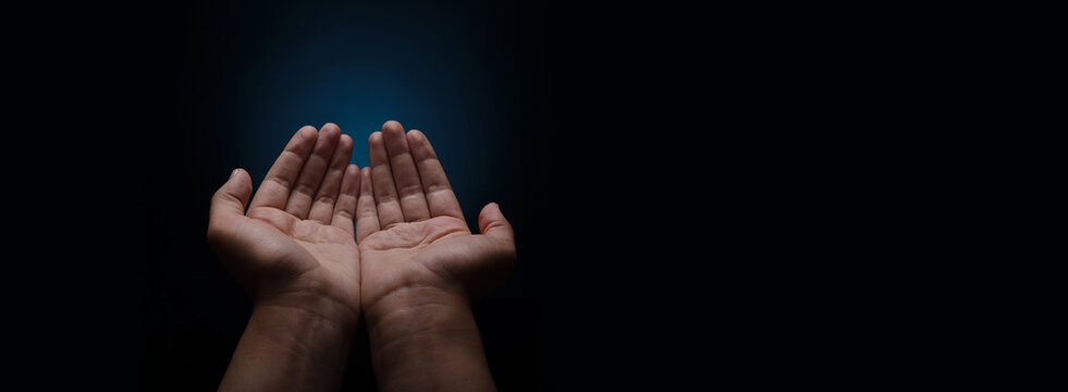 Praying hands with faith in religion and belief in God on dark  background, palm opening, begging gesture, panoramic layout