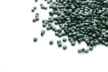Vegetarian vitamins from Spirulina are scattered on a white background