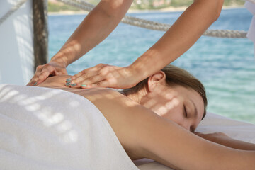 Woman having back massage in spa tent on the beach.	