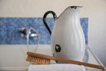 Spa bathroom setting: vintage enamel jug, brush and towel. 