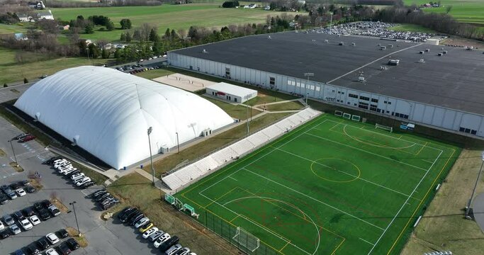 Massive warehouse and sports dome, outdoor field. Indoor sports arena. Aerial view.