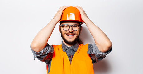 Studio portrait of happy young engineer in orange equipment on white background.