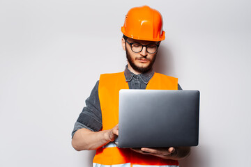 Portrait of young construction engineer using laptop on white background.