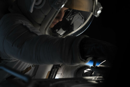 Female astronaut performing spacewalk, working on a outer part of a space craft