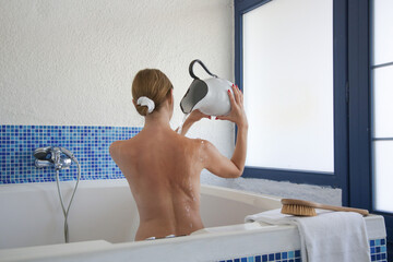 Back view of young woman in tub in spa	