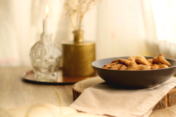 Plate of chocolate chip cookies and sugar cookies, vintage books and reading glasses, candle and flower on the table. Hygge at home. Selective focus.