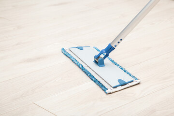 Microfiber mop pad with stick on light laminate background. Floor washing at home, office or other...