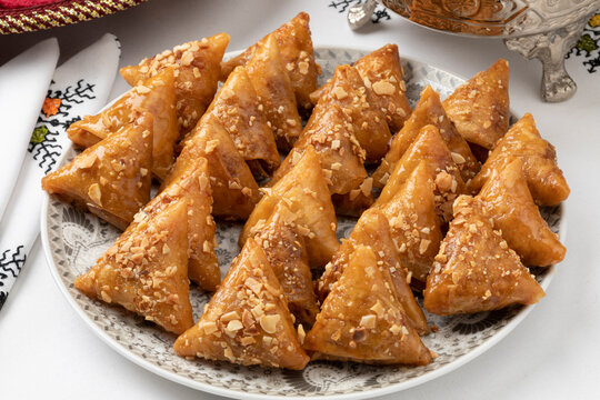 Dish with fresh traditional Almond briouats, coated in warm honey and filled with almond paste flavored with cinnamon and orange flower water close up   