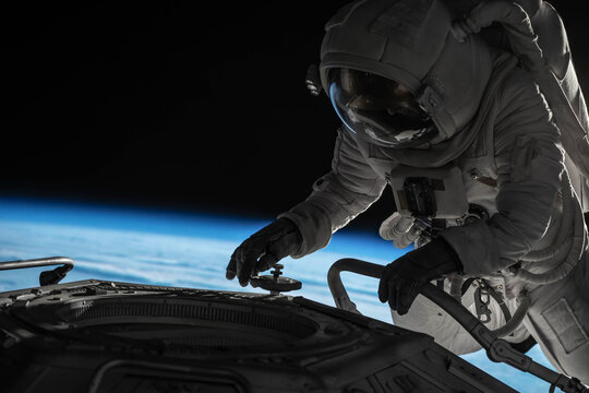 Female astronaut performing spacewalk, working on a outer part of a space craft