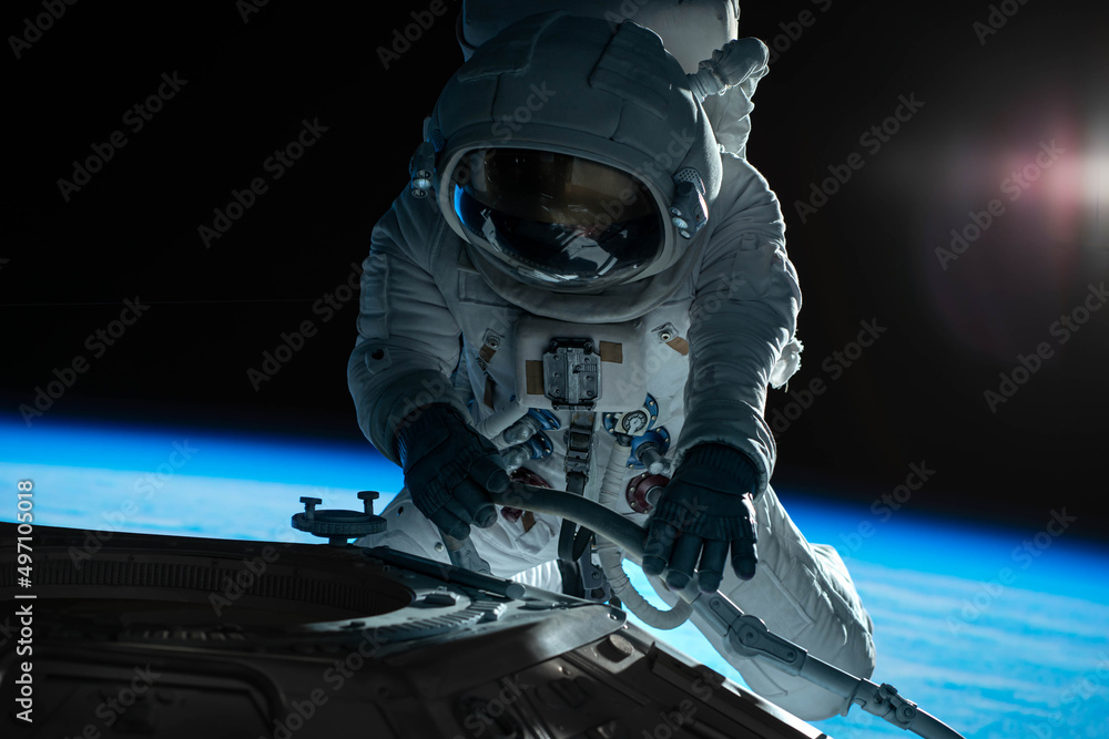 Wall mural female astronaut performing spacewalk, working on a outer part of a space craft
