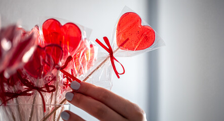Red heart-shaped lollipops on the counter of a candy store.