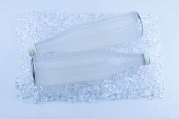 A white bottle with a soda drink on ice isolated.