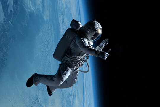 Female astronaut having a video call on her phone while performing spacewalk in deep space, Earth in the background - Powered by Adobe