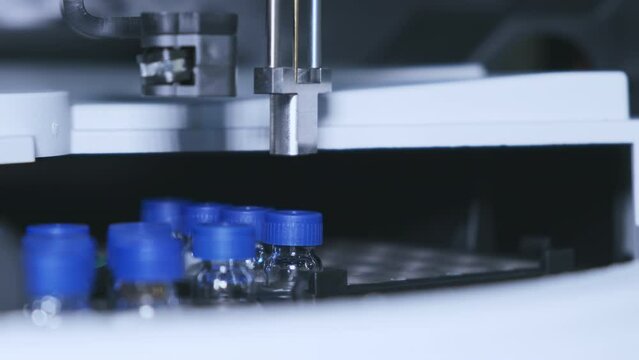 Glass vials with blue caps rotate in HPLC Autosampler at professional chemical laboratory. Development of new modern vaccine extreme closeup