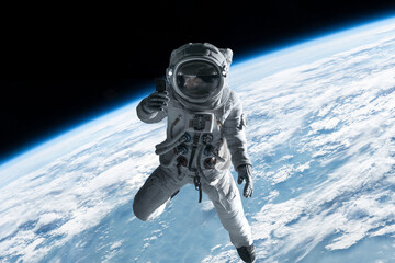 Female astronaut having a video call on her phone while performing spacewalk in open space, Earth in the background