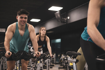 people on bikes in spinning class in modern gym, exercising on stationary bike. group of athletes...