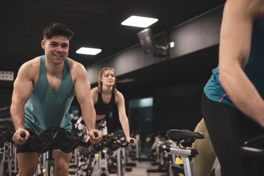 people on bikes in spinning class in modern gym, exercising on stationary bike. group of athletes training on exercise bike
