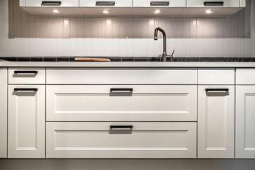 White kitchen cabinets with metal pulls or knobs on the doors.