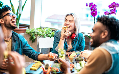 Multicultural friends eating together at luxury pub restaurant - Life style concept with trendy multiracial people having fun on happy hour at bar eatery - Vivid filter with focus on central woman