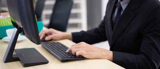 Hand of male employee typing on computer keyboard at desk in the office. working, typing work...