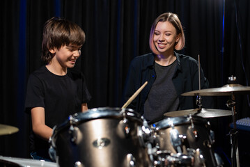 Obraz na płótnie Canvas Young woman teaching boy to play drums.