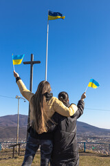 Women with flags of Ukraine against the background of the sky and mountains.