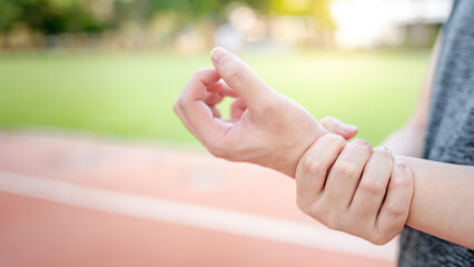 Athlete male hand holding his painful wrist for healing the pain while doing exercise outdoor....