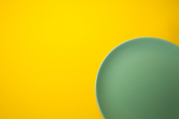 Empty green plate on a yellow background. Top view