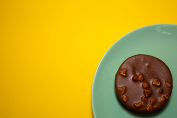 A picture of single homemade chocolate tart on yellow background. Same colour subject and background concept
