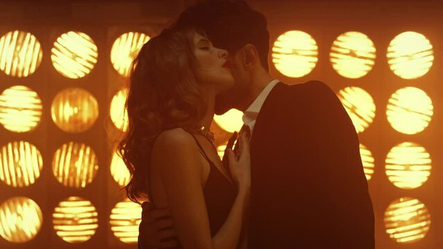 Hot woman seducing man in club lights. Young couple performing intimate dance.