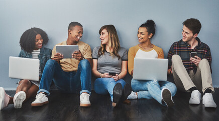 The age of digital citizenship. Studio shot of a group of young people using wireless technology against a gray background.